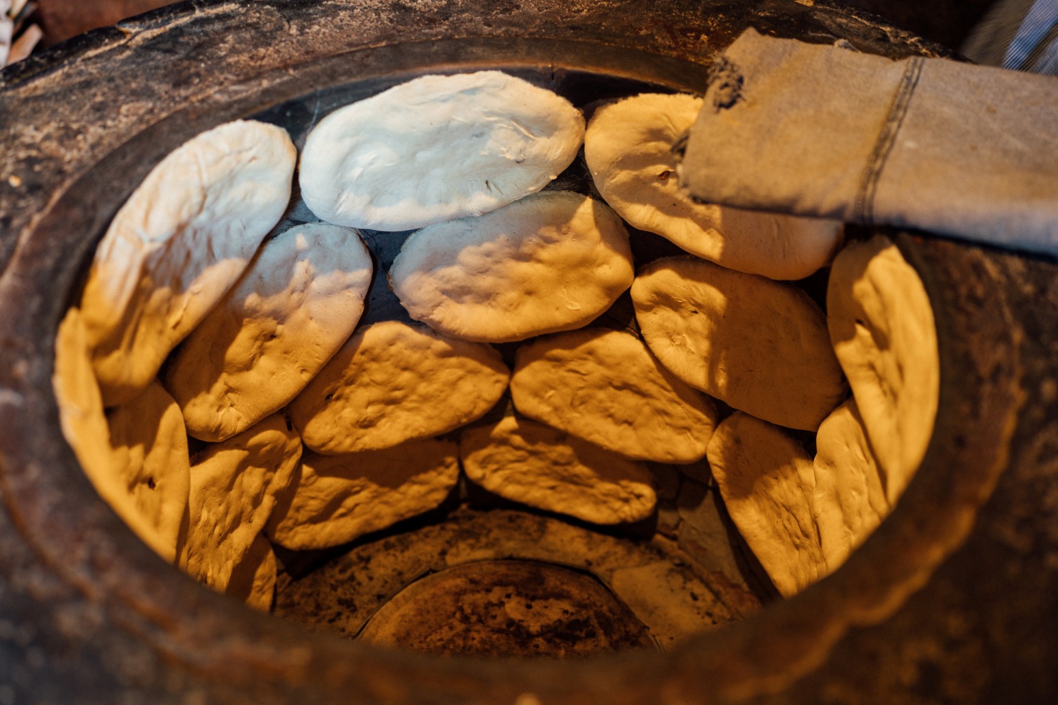Flatbread dough sticking to the walls of a traditional Georgian tone (clay tandoor) oven as it bakes