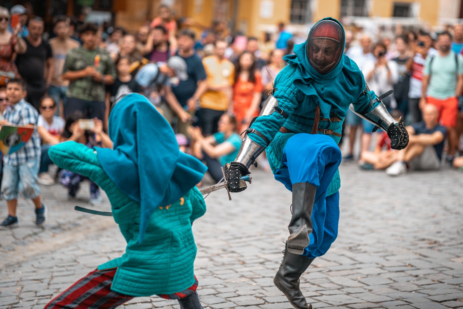 Two performers in medieval armour reenacting a sword fight for a crowd on the cobbled streets of Sighișoara