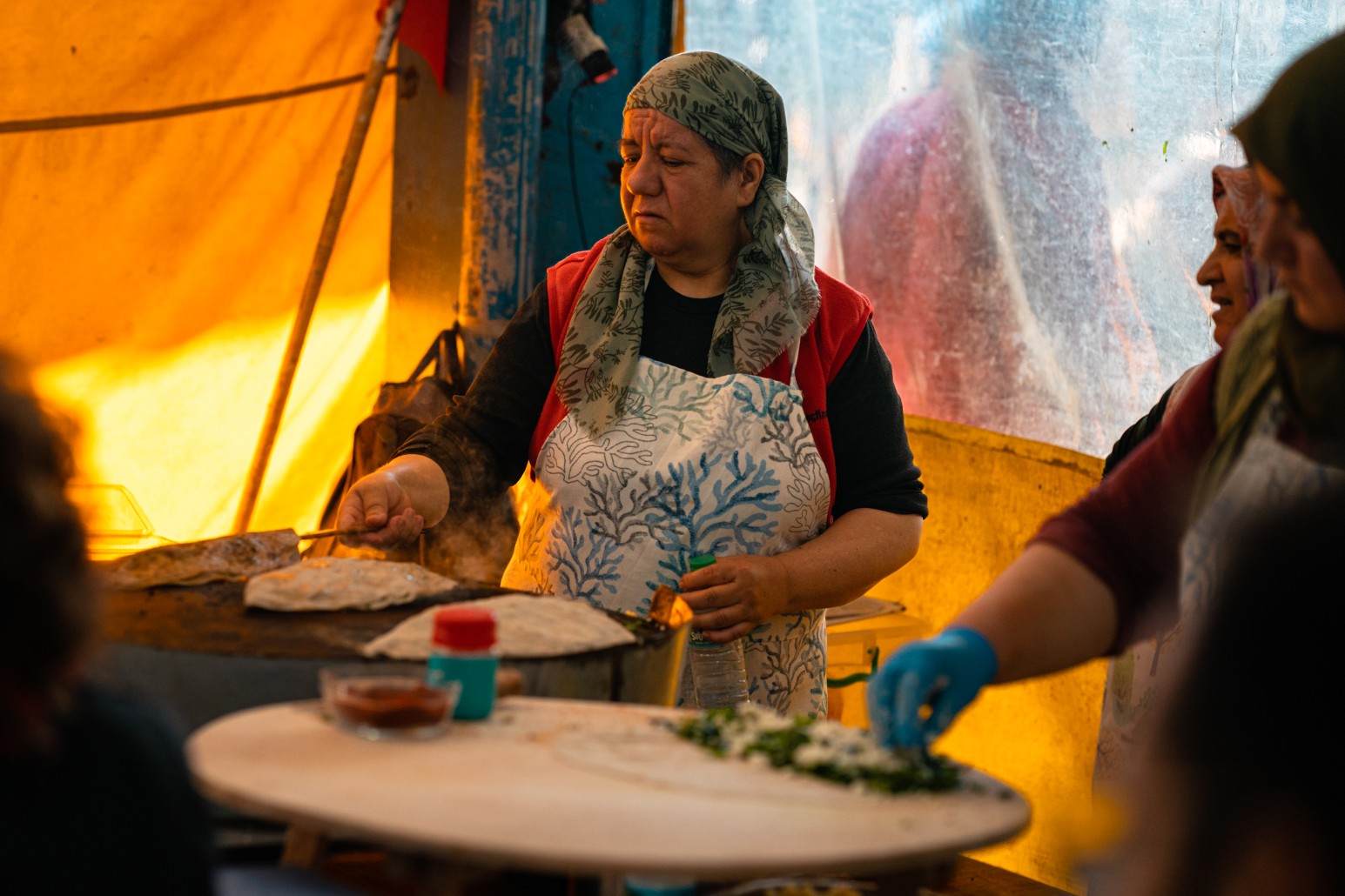 Woman in a headscarf cooking gözleme on a griddle at an outdoor food stall in Turkey