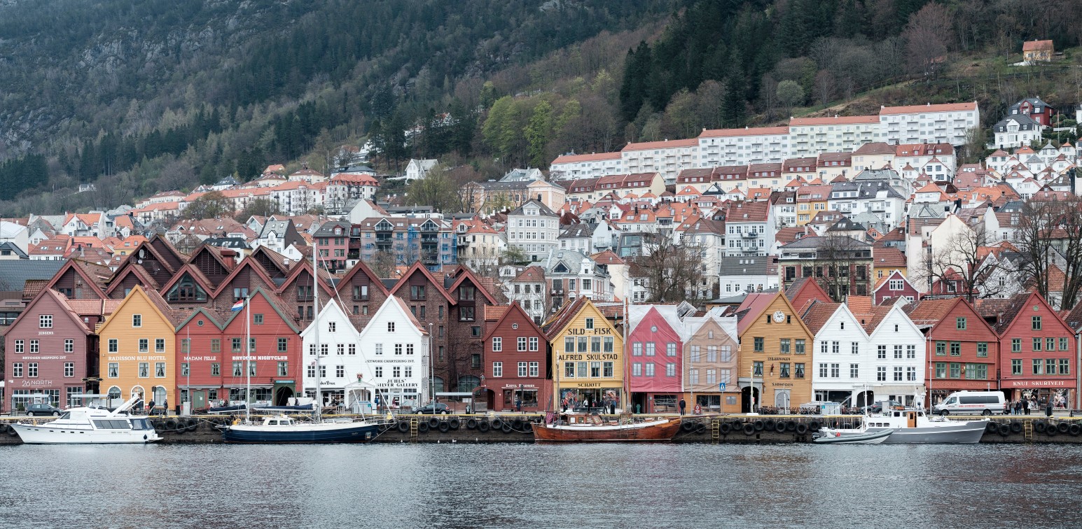 The colourful wooden buildings of Bryggen along the harbour in Bergen, Norway, with hillside houses behind