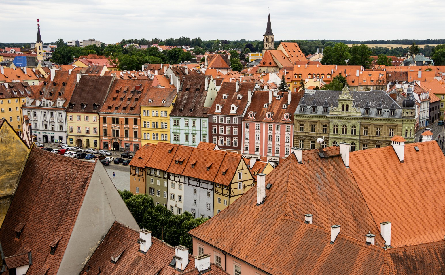 A rooftop view over the colourful historic buildings and orange-tiled roofs of Cheb's old town square.
