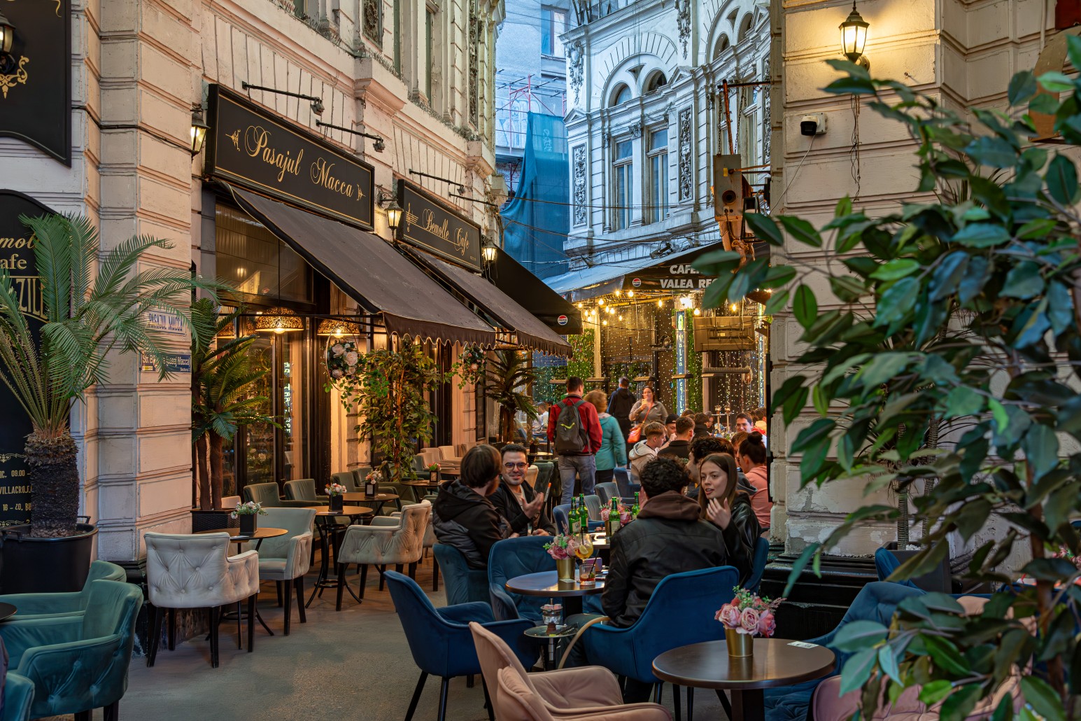 People dining at outdoor cafés in Pasajul Macca-Vilacrosse, a covered glass-roofed arcade in Bucharest’s old town