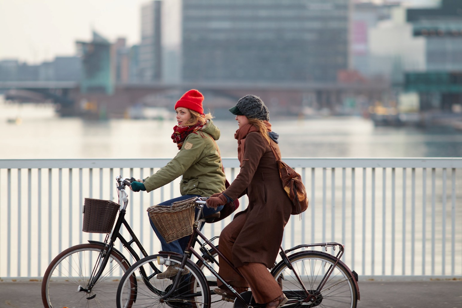 Two women cycling along a waterfront path in Copenhagen, Denmark