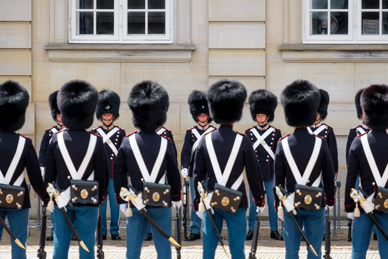 Royal Life Guards in ceremonial bearskin hats and uniforms standing in formation outside Amalienborg Palace, Denmark