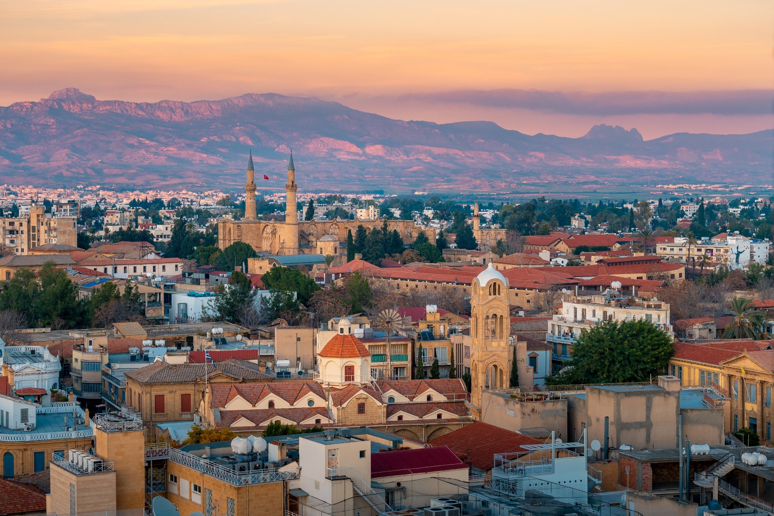 Aerial view of Nicosia, Cyprus at sunset, with the Selimiye Mosque minarets and mountains in the background