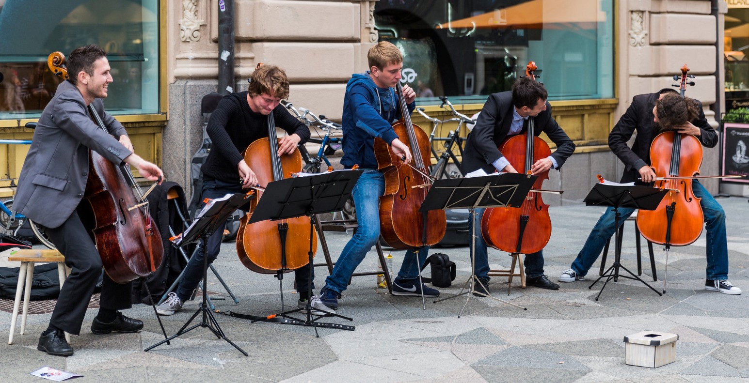 A group of cellists performing outdoors on a street during The Night of the Arts festival in Helsinki, Finland