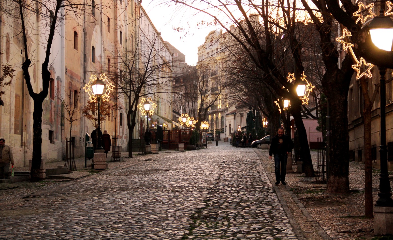 Cobblestone street in Skadarlija, Belgrade’s bohemian quarter, lined with historic buildings and star-shaped string lights at dusk