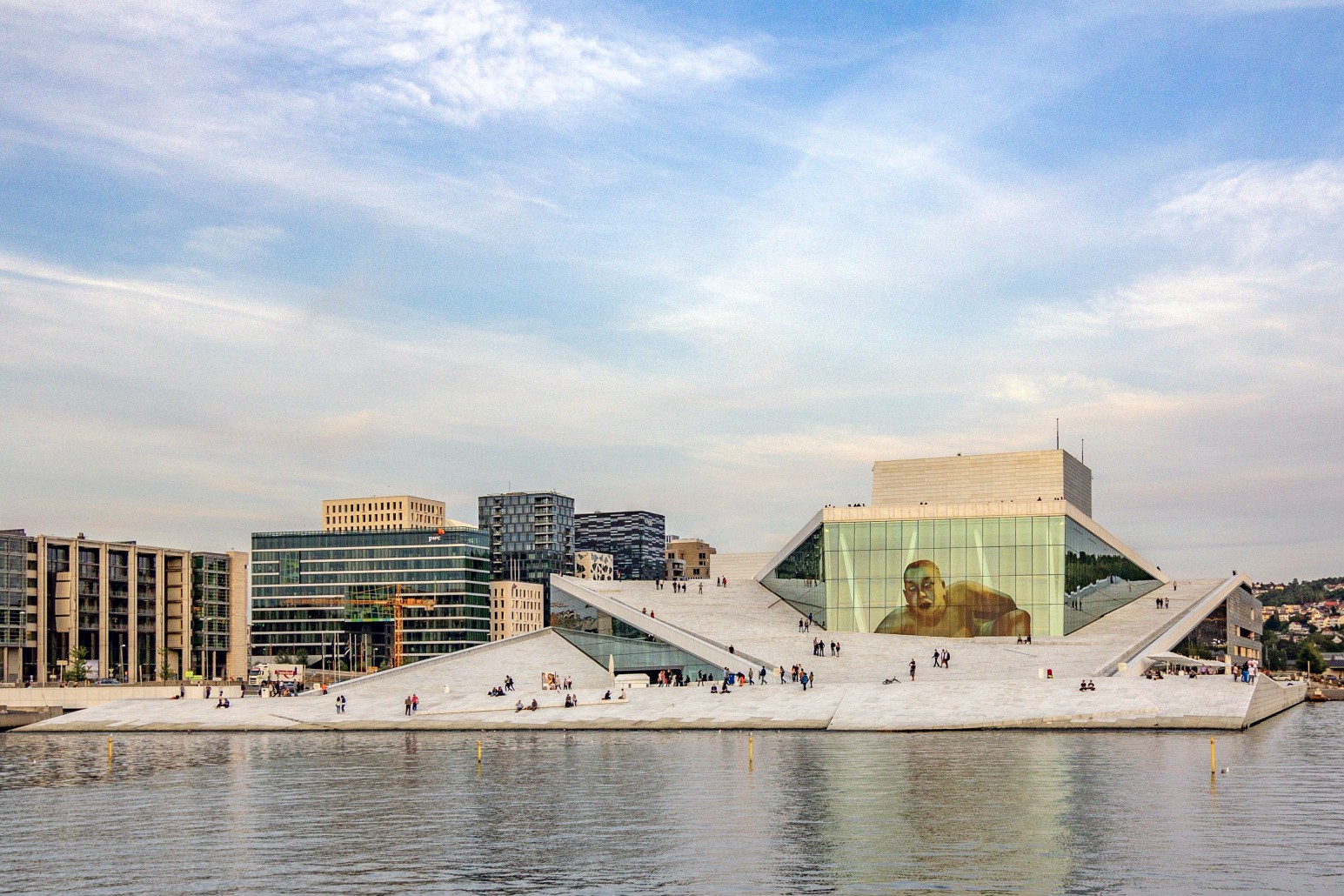 The angular white marble roof of the Oslo Opera House, Norway, with people walking on its sloped exterior