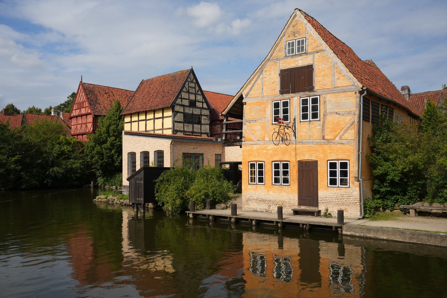 Traditional half-timbered houses reflected in the water at Den Gamle By open-air museum in Aarhus, Denmark