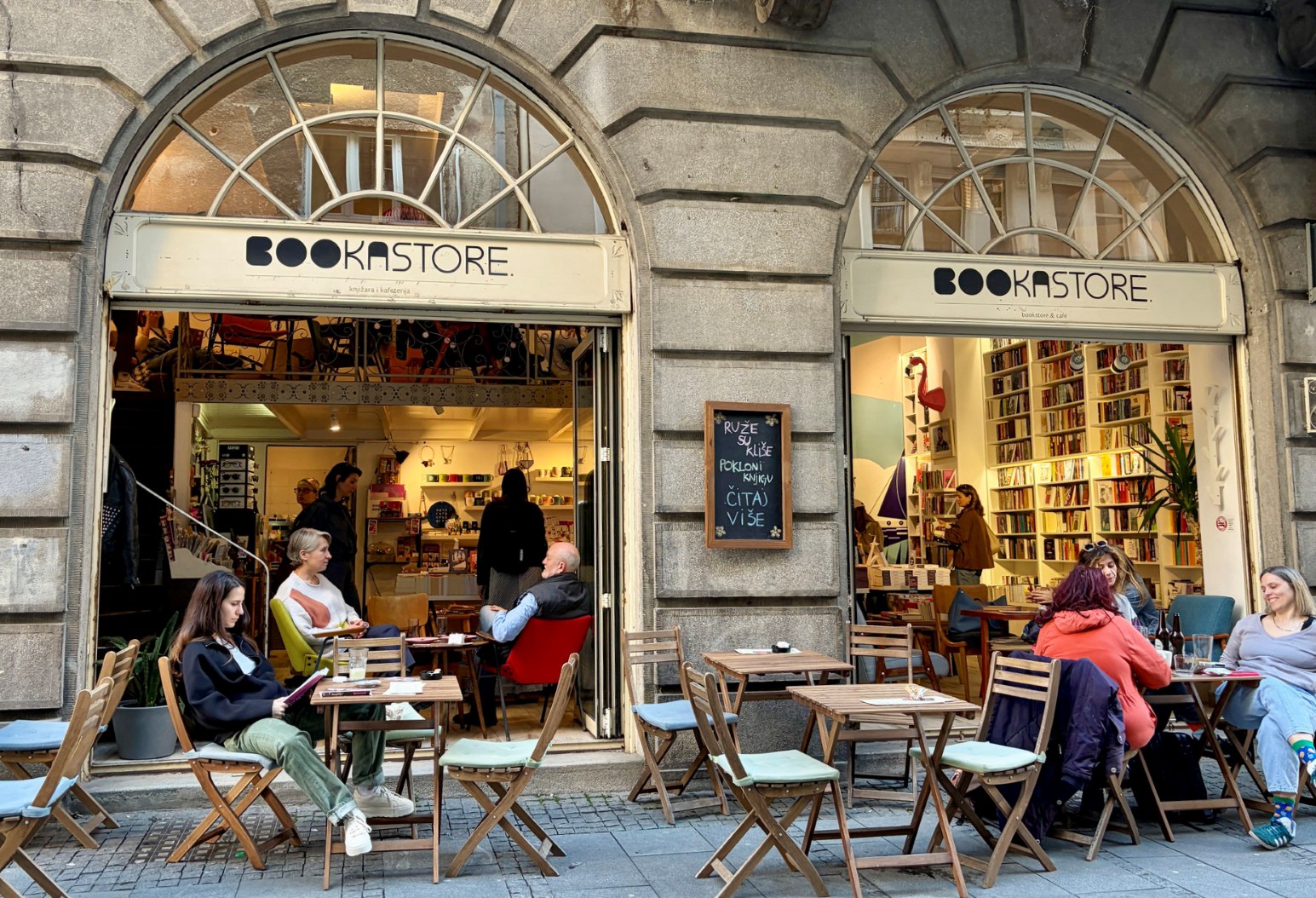 Exterior of Bookastore, a bookshop and café in Belgrade, with customers seated at outdoor tables beneath arched stone doorways