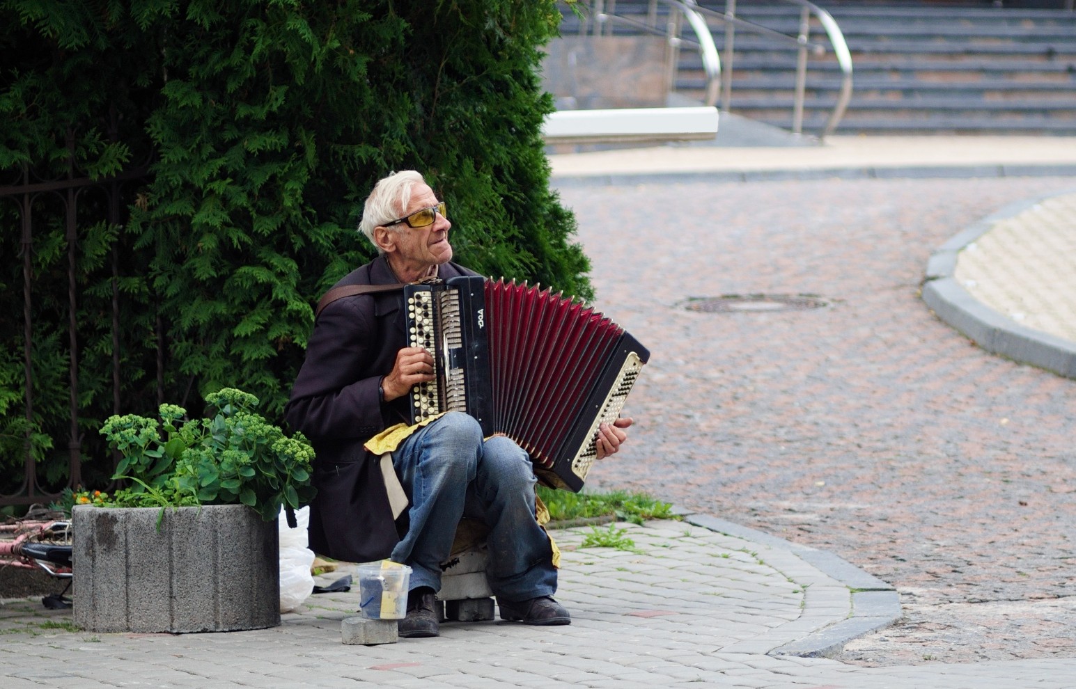 An elderly street musician playing an accordion on a cobblestone street in Ukraine