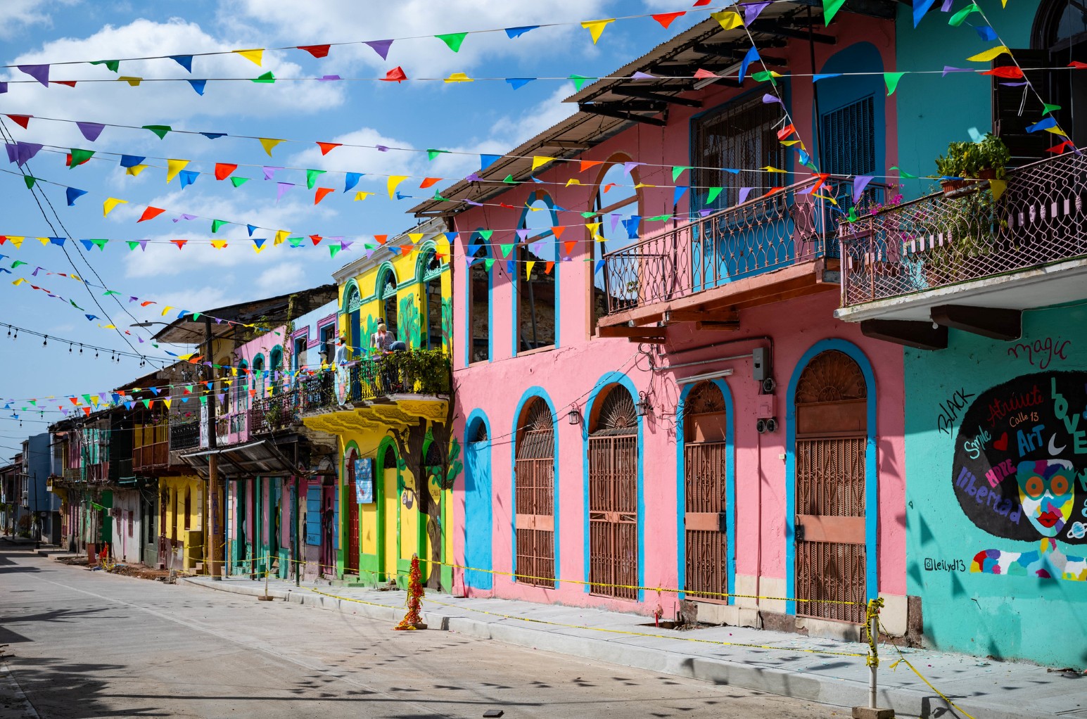 A street of brightly painted pink, yellow and turquoise buildings strung with colourful bunting in Panama City