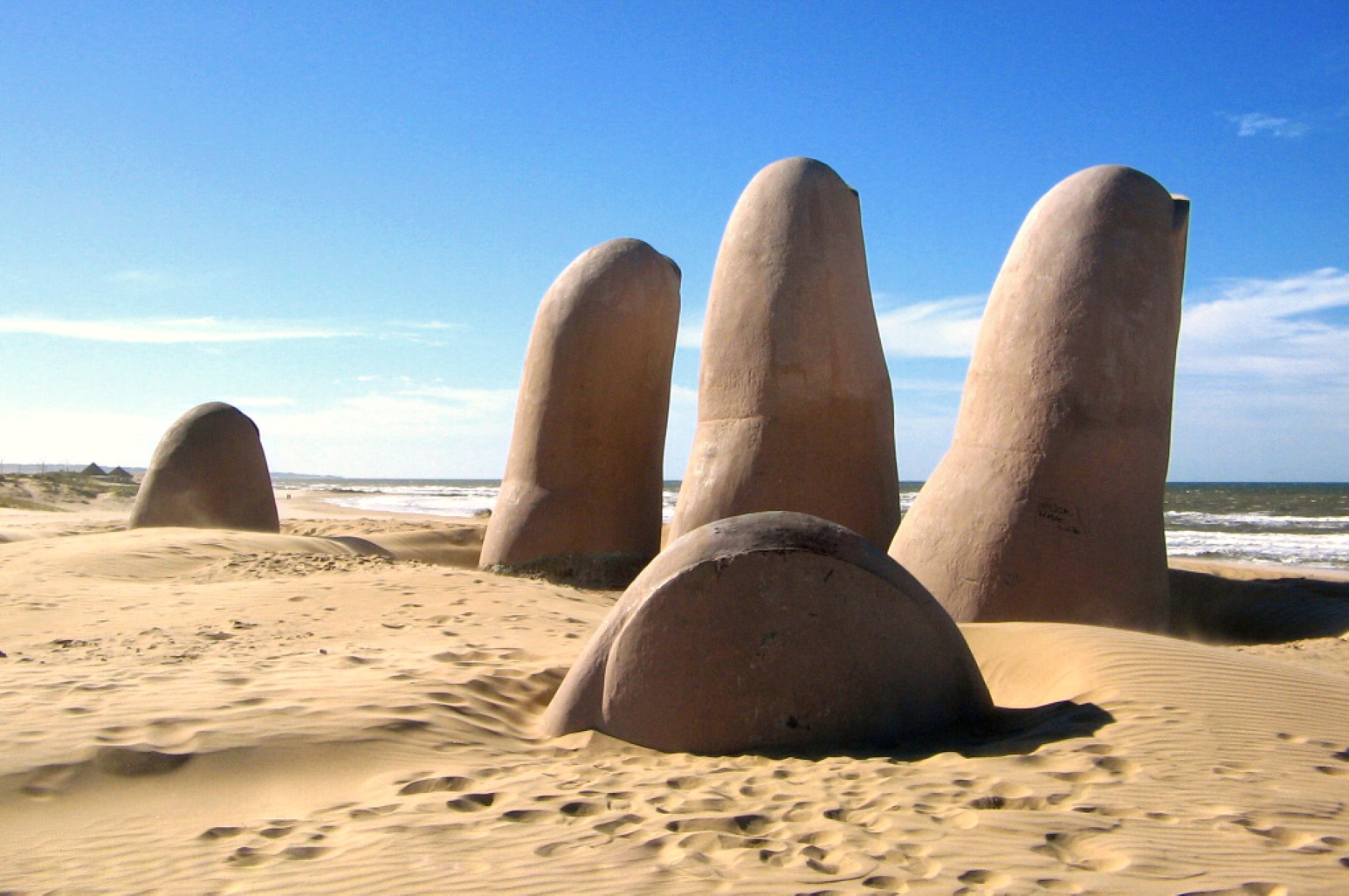 La Mano, the giant concrete sculpture of fingers emerging from the sand on the beach at Punta del Este, Uruguay, with the ocean and a clear blue sky behind