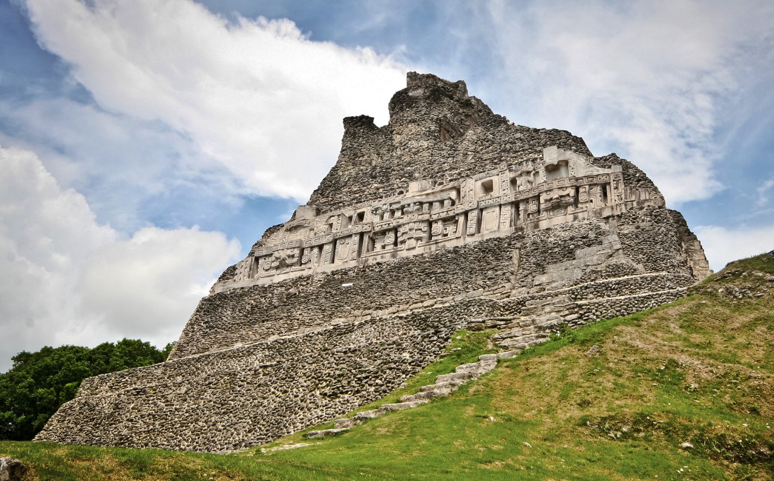 El Castillo, the main pyramid at the ancient Maya site of Xunantunich near San Ignacio, Belize, with its carved stone frieze and grassy slopes beneath a partly cloudy sky